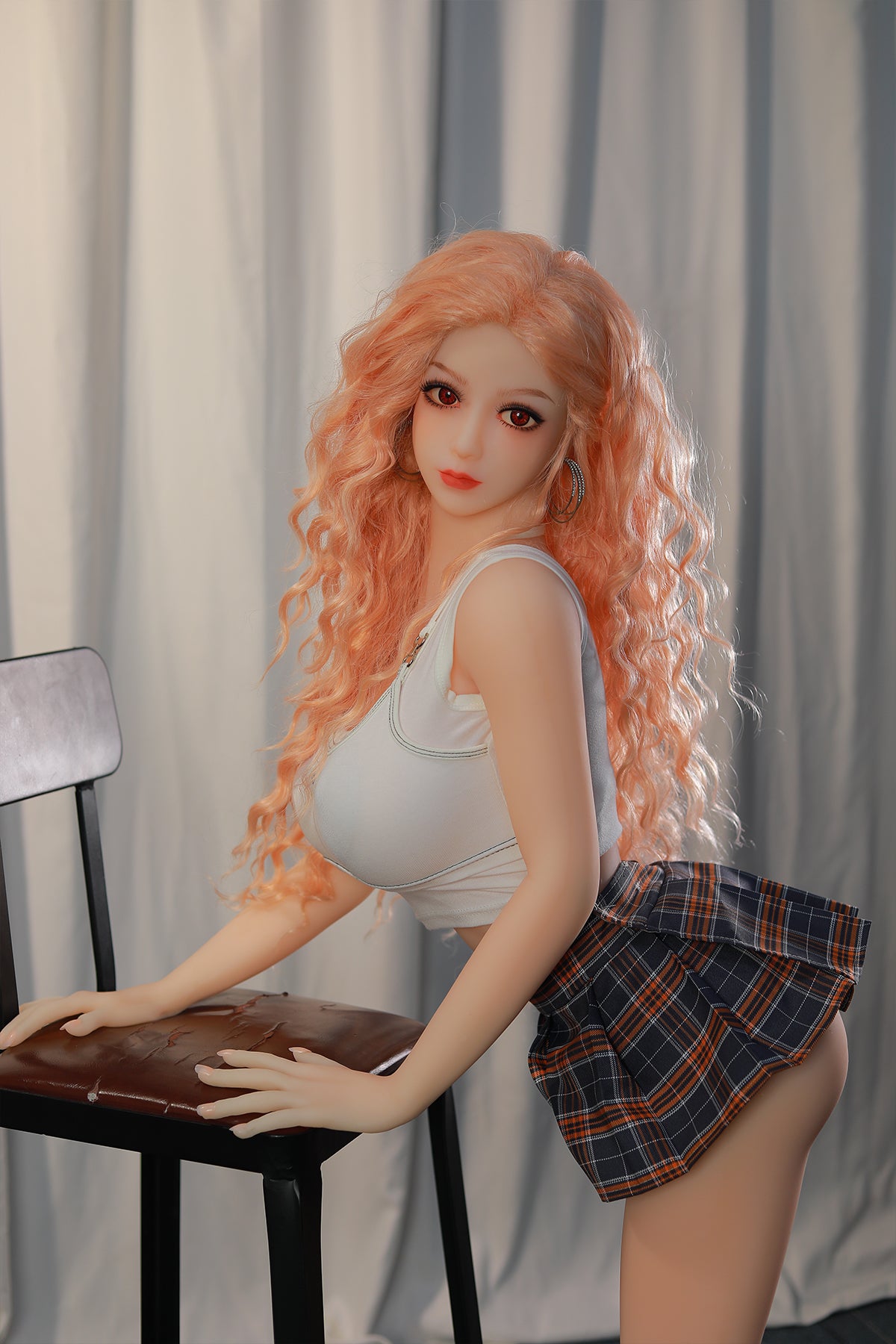 148cm TPE Sex Doll Maya Upper body and hip crop of a figure with pink hair white top and plaid skirt leaning on a chair