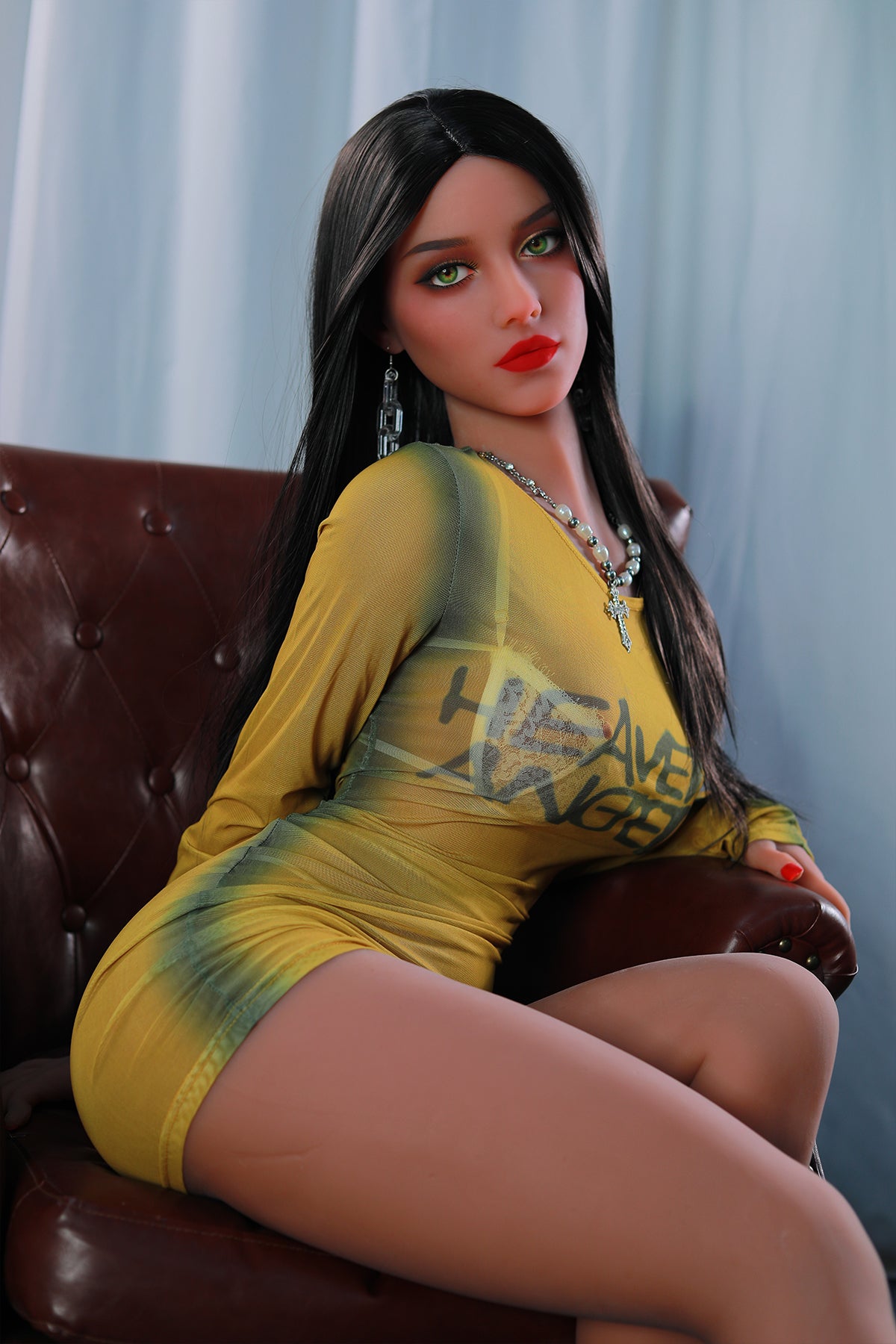 165cm TPE Sex Doll Sienna Seated shot of a woman in a yellow mesh dress leaning back in a brown leather chair medium crop