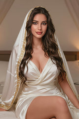 162cm TPE Sex Doll Olive Satin dress with deep V-neck and gold trim Seated pose on bed legs visible but not cropped Neutral background clear upper-body focus